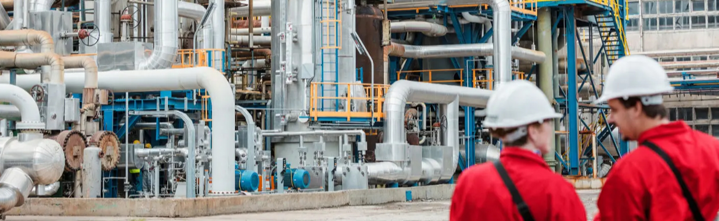 An engineer in a hard hat at a refinery